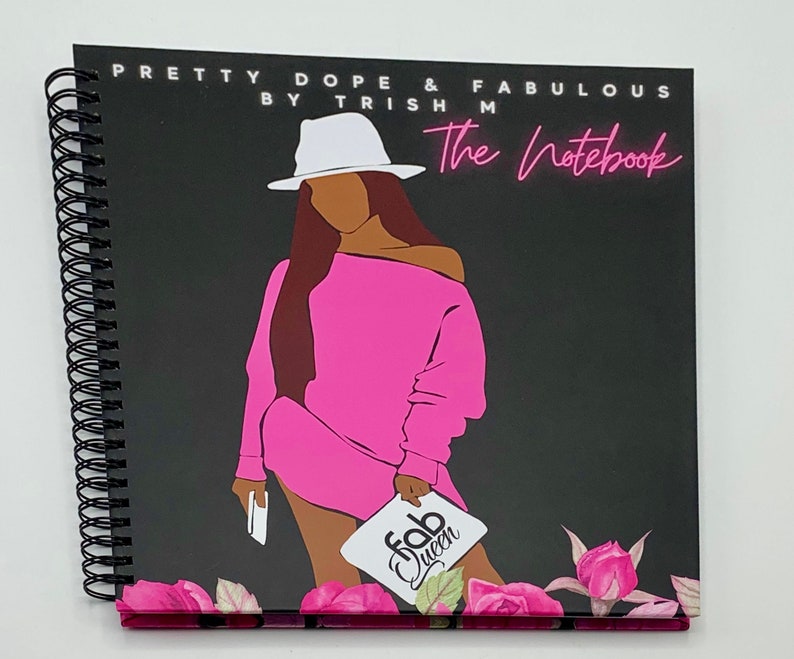 Peut inclure: Un carnet &agrave; spirales noir avec une illustration rose et noire d'une femme portant un chapeau blanc et une robe rose. La couverture du carnet porte le texte "Pretty Dope & Fabulous by Trish M The Notebook" et un autocollant rose et blanc qui dit "Fab Queen".