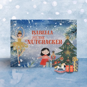 May include: A children's book cover with the title "Isabella and the Nutcracker". The illustration depicts a ballerina, a young girl, a Christmas tree, and presents, set against a snowy blue backdrop. Festive and whimsical design.