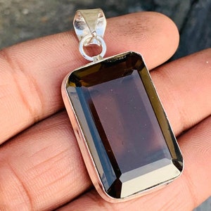 May include: A silver pendant featuring a large, rectangular, dark brown gemstone. The gemstone is faceted and has a shiny, polished finish.