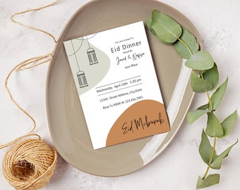 May include: A beige and brown invitation card with a decorative design of hanging lanterns. The text reads "You are invited to Eid Dinner hosted by Javed & Nafisa xxxx Place Wednesday April 10th 5:30 pm 12345 Street Address, City, State Rsvp to XXXX at 123.456.7891 Eid Mubarak".