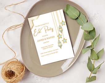 Puede incluir: Una tarjeta de invitación blanca con letras doradas y un borde decorativo. La tarjeta dice "You Are Invited To A Eid Party Hosted By JAVED & NAFISA xxx Place Wednesday April 10th Begins At 5.30 pm 12345 Street Address, City, State Rsvp To XXXX At 123.456.7880". La tarjeta está decorada con una cadena de cadenas doradas con linternas y estrellas azules y blancas.