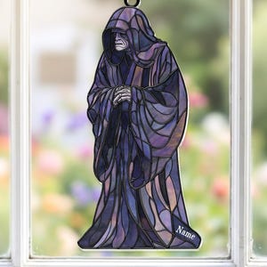 May include: A stained glass window hanging featuring a robed figure with a hood. The figure is primarily shades of purple and blue, with a few tan accents. The figure is hanging from a chain and has the word "Name" on the bottom.