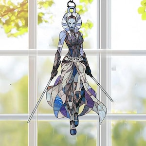 May include: Stained glass figure of a female warrior with two light sabers, hanging from a chain. The figure is in shades of blue, purple, and gray, with the name "Anesa" on the chest. The background is a window with a view of green foliage.