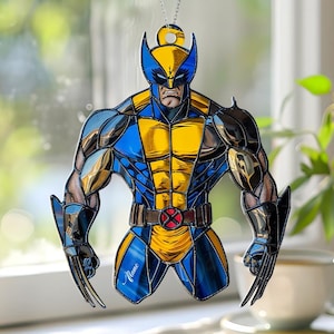 May include: A hanging decoration featuring the superhero Wolverine. The figure is in a classic pose, with a blue and yellow costume, and metal claws extended. The decoration is suspended by a silver chain. The background is a window with natural light.