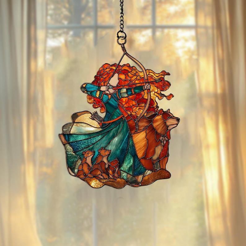 May include: Stained glass suncatcher featuring a red-haired archer aiming a bow, with a bear and three cubs. The archer wears a teal and blue dress. The bear and cubs are brown. The suncatcher hangs from a chain.