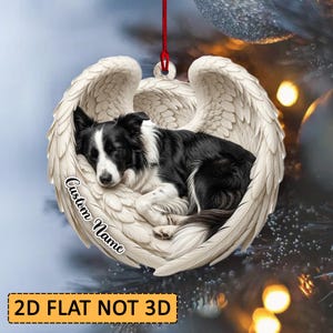 Op de afbeelding: Een plat, rond hangend ornament met een zwart-witte Border Collie die opgerold slaapt in een paar grote, gedetailleerde witte engelvleugels. De tekst Custom Name is in zwarte letters op de witte veren aan de linkerkant gedrukt.