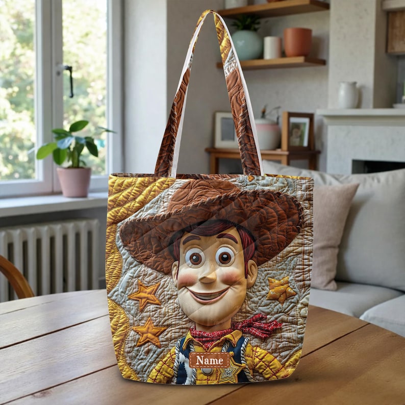 May include: A quilted tote bag featuring a large graphic of a cowboy character wearing a brown hat, a yellow shirt, and a blue vest. The background includes yellow star shapes and a brown rectangular patch with the word Name printed in white.