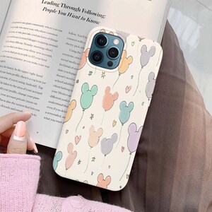 Puede incluir: Una funda de tel&eacute;fono con un dise&ntilde;o caprichoso que presenta globos en forma de Mickey Mouse de colores pastel flotando sobre un fondo crema. La funda tiene un acabado liso e incluye corazones y estrellas. La funda est&aacute; dise&ntilde;ada para un tel&eacute;fono inteligente.