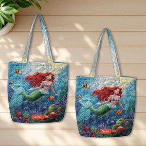 Puede incluir: Dos bolsos de tela acolchados con un estampado submarino que muestra una sirena de pelo largo y rojo con cola verde. El dise&ntilde;o incluye corales coloridos, peces tropicales y un cangrejo rojo. Cada bolso tiene una etiqueta rectangular con Name.