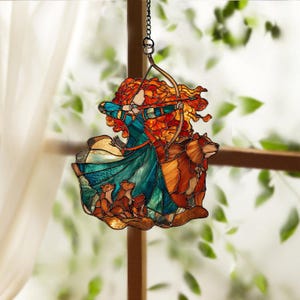 May include: Stained glass suncatcher featuring a red-haired woman with a bow and arrow, a brown bear, and three smaller animals. The woman wears a teal and blue dress. The suncatcher hangs from a chain.