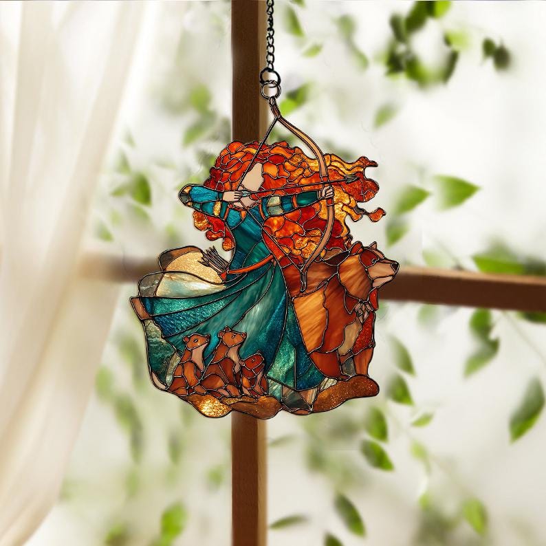 May include: Stained glass suncatcher featuring a red-haired woman with a bow and arrow, a brown bear, and three smaller animals. The woman wears a teal and blue dress. The suncatcher hangs from a chain.