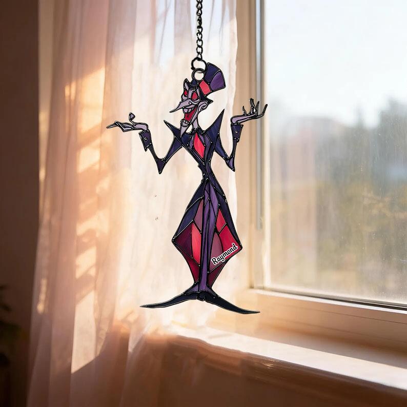 May include: A stained glass suncatcher depicting a cartoonish figure in a top hat and suit. The figure is primarily black, purple, and red, with the name "Raymond" visible. It hangs from a chain in front of a window.