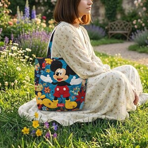 May include: A quilted tote bag featuring a central graphic of Mickey Mouse wearing red shorts and yellow shoes, set against a vibrant blue background with colourful floral patterns and a small red rectangular label with the text Name.