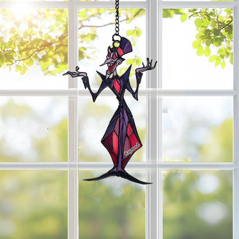 May include: A stained glass suncatcher depicting a cartoon character with a top hat, long nose, and outstretched arms. The figure is in shades of purple, red, and black, with the name "Raymond" visible. It hangs from a chain in front of a window.