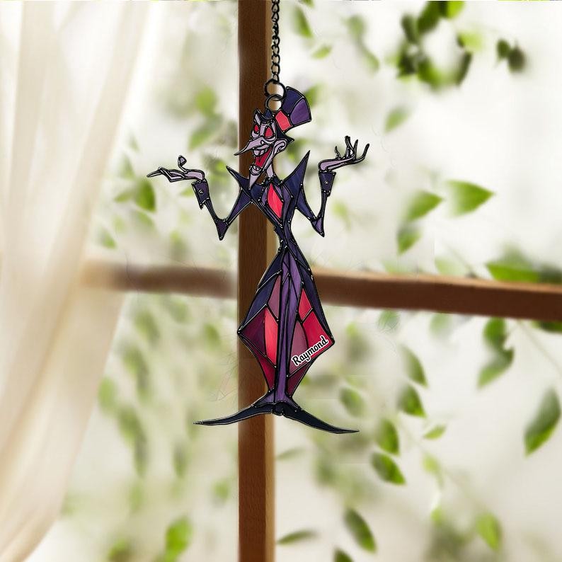 May include: A stained glass suncatcher depicting a cartoon character in a purple and red outfit, with a matching hat. The character has a long nose and is posed with arms outstretched. The name "Raymond" is visible on the design.