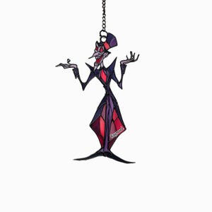 May include: A stained glass ornament depicting a stylized character in a purple and red suit, with a long nose and a top hat. The ornament is suspended by a chain and features the name "Raymond".
