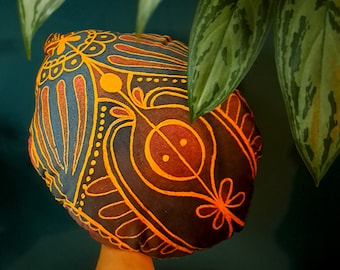 May include: A dark brown fabric shower cap with a colorful abstract design featuring yellow, orange, and red accents. The design includes a large, stylized eye shape.