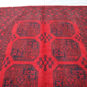 Puede incluir: Una alfombra estampada en rojo y negro con un dise&ntilde;o central de cuatro formas octogonales. La alfombra tiene un borde con un patr&oacute;n geom&eacute;trico repetitivo. El dise&ntilde;o es sim&eacute;trico y tradicional, adecuado para la decoraci&oacute;n del hogar.