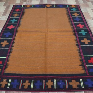 May include: A brown wool rug with a black border and colorful cross patterns. The rug has a traditional design and is perfect for adding a touch of warmth and color to any room.