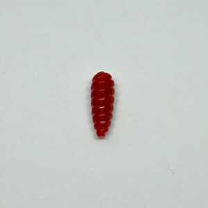 Puede incluir: Un se&ntilde;uelo de pesca de pl&aacute;stico rojo con forma de gusano.