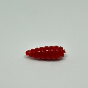 Puede incluir: Un se&ntilde;uelo de pesca de pl&aacute;stico rojo en forma de gusano segmentado.