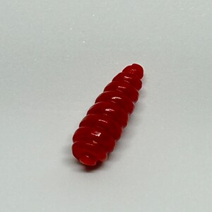 Puede incluir: Un se&ntilde;uelo de pesca de pl&aacute;stico rojo, segmentado, con forma de gusano.