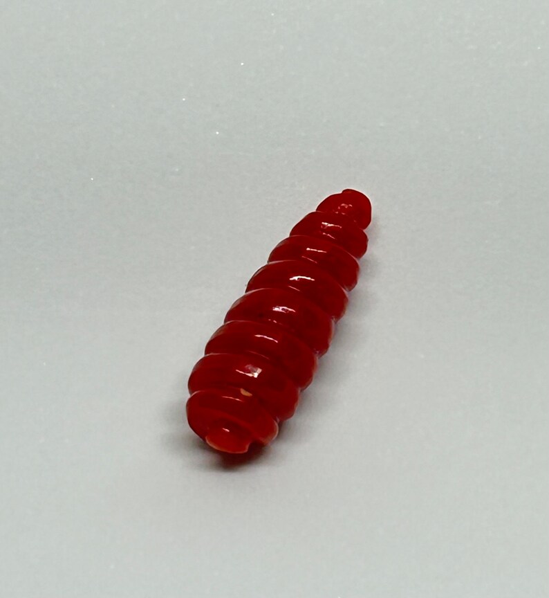 Puede incluir: Un se&ntilde;uelo de pesca de pl&aacute;stico rojo, segmentado, con forma de gusano.