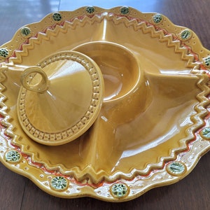 May include: A yellow ceramic serving dish with four sections and a removable lid. The dish has a scalloped edge and is decorated with green and orange floral designs.