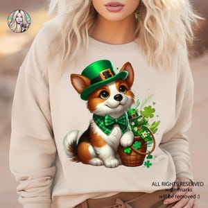 Może przedstawiać: Biała bluza z nadrukiem kreskówkowego corgi w zielonym kapeluszu leprechauna trzymającego garnek złota. Corgi ma zieloną kratkowaną muszkę.