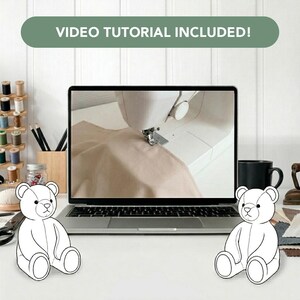 May include: A laptop screen displays a sewing machine stitching beige fabric, with the text VIDEO TUTORIAL INCLUDED! above. Two white line-art teddy bear illustrations sit on either side of the laptop on a desk with sewing supplies nearby.
