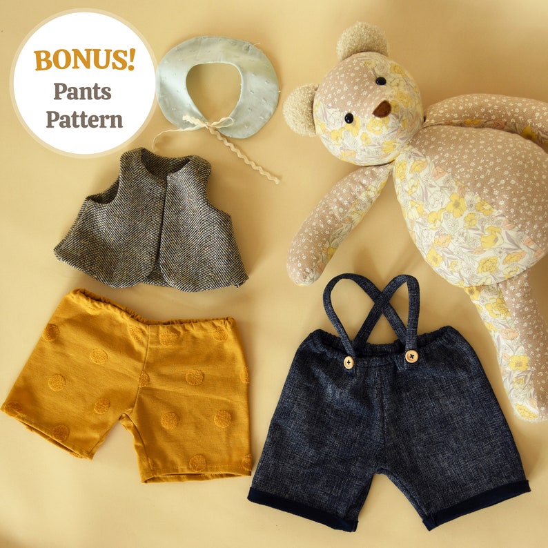 May include: A set of doll clothes including a brown and white vest, a pair of yellow shorts with brown polka dots, and a pair of blue denim overalls with brown buttons. The doll clothes are laid out on a beige surface next to a floral patterned teddy bear.