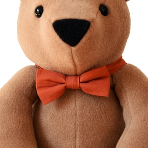 Plush memory bear with bow tie in terracota color on his neck