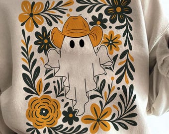 May include: Beige sweatshirt with a cartoon ghost wearing a cowboy hat. The ghost is framed by a floral design with yellow and dark green flowers and leaves. The sweatshirt is a neutral colour.