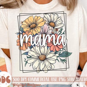 May include: A white t-shirt featuring a floral design and the word "mama" within a black frame. The flowers are yellow, pink, and white.