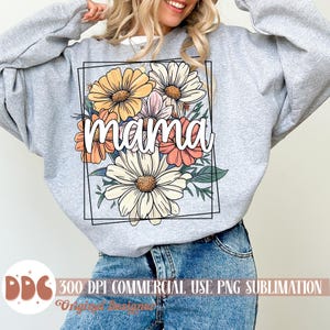 May include: A grey sweatshirt featuring a floral design and the word "mama" in white lettering. The flowers are in shades of yellow, orange, pink, and white.
