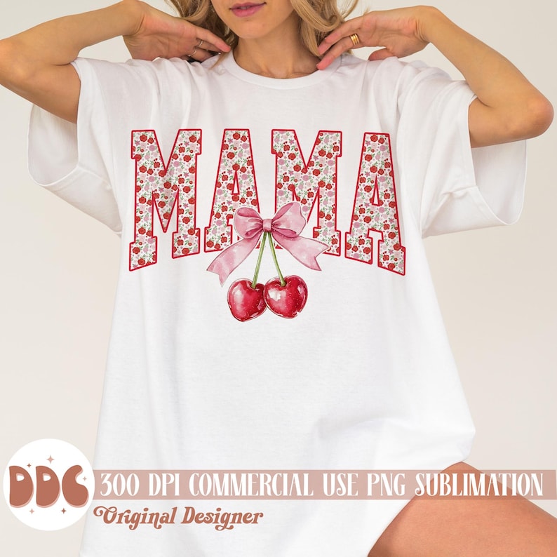 May include: White t-shirt with the word "MAMA" in red letters filled with a floral pattern. A pink bow and two red cherries are below the word. The shirt also has the text "300 DPI COMMERCIAL USE PNG SUBLIMATION Original Designer".