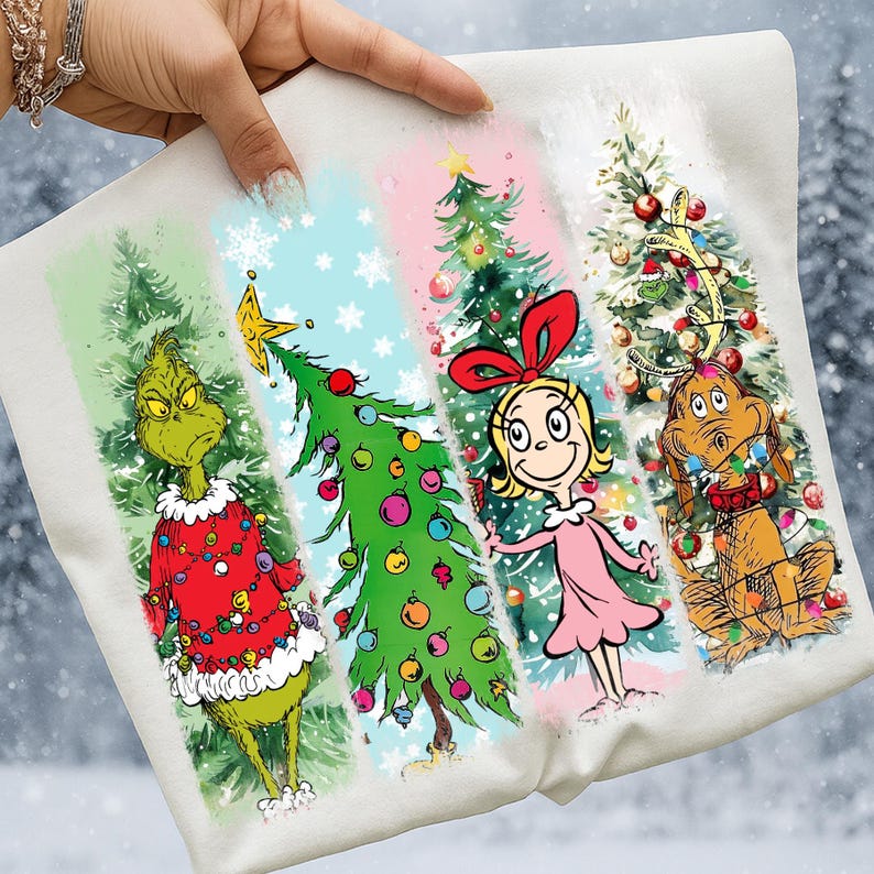 Op de afbeelding: Wit kerst-thema grafisch T-shirt met de Grinch, een versierde kerstboom, Cindy Lou Who en Max de hond. Het ontwerp bevat kleurrijke illustraties op een witte achtergrond, perfect voor de feestdagen.