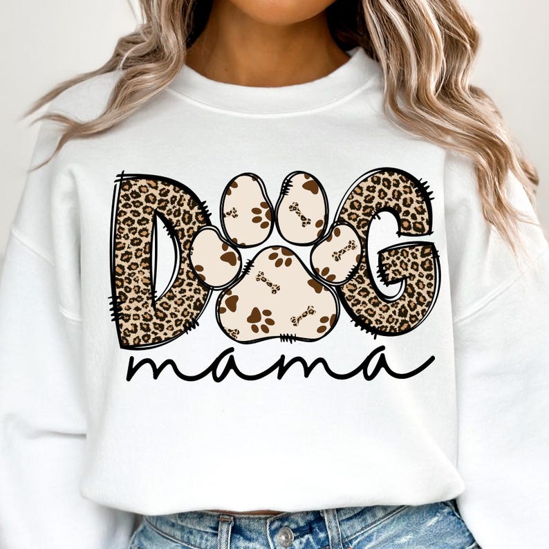 Pu&ograve; includere: Felpa bianca con un design a stampa leopardata marrone e nera che dice "DOG mama" con un'impronta di zampa al centro.