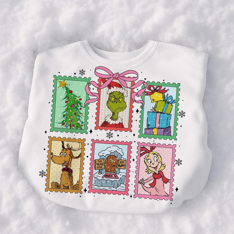 May include: White sweatshirt featuring six postage stamp-style images of characters and scenes from a holiday story. The images include a Christmas tree, a green character, wrapped gifts, a dog, a door with text, and a girl. A pink bow is at the top.