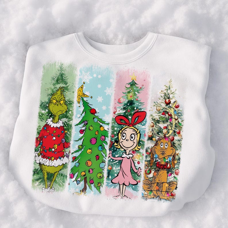 Op de afbeelding: Witte sweatshirt met een kleurrijk kerstthema. Het ontwerp toont de Grinch, een kerstboom, Cindy Lou Who en hond Max, elk in een apart verticaal paneel. De Grinch draagt een rode trui en Cindy Lou Who een roze jurk.
