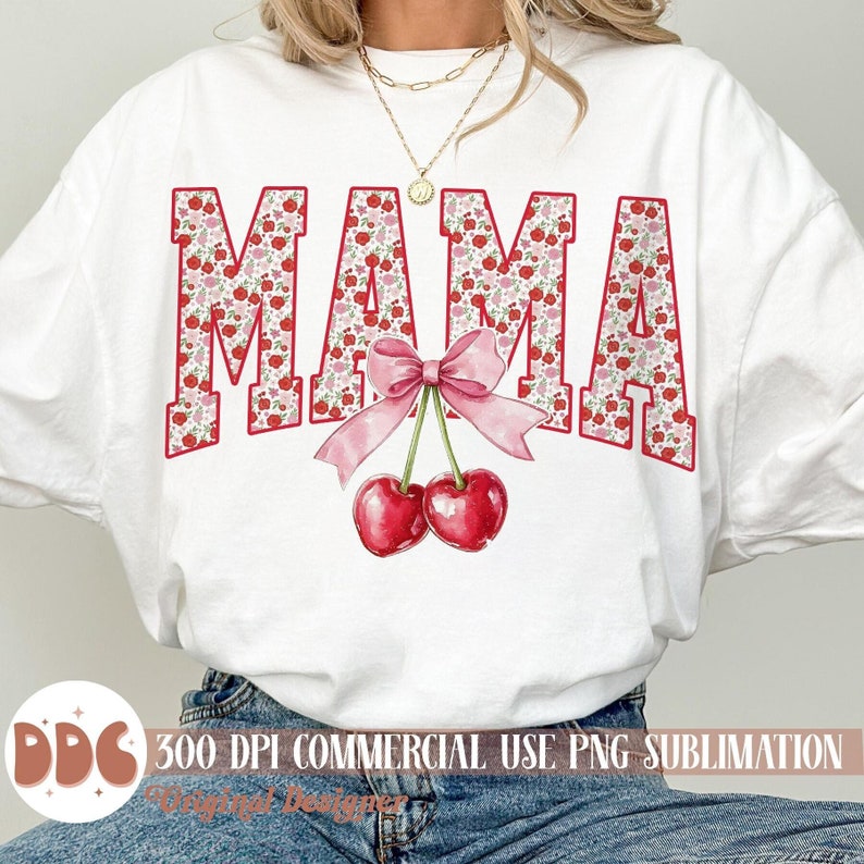 May include: White t-shirt with the word "MAMA" in red block letters filled with a floral pattern. A pink bow and two red cherries are centered below the word. The shirt is a sublimation design.