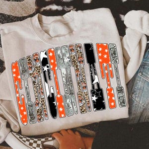 Puede incluir: Sudadera beige con la palabra "Gameday" en un dise&ntilde;o estilizado. Las letras incorporan patrones como estrellas naranjas, efectos de bola de discoteca, estampado de leopardo y patrones de estrellas en blanco y negro. Un estilo casual y c&oacute;modo.