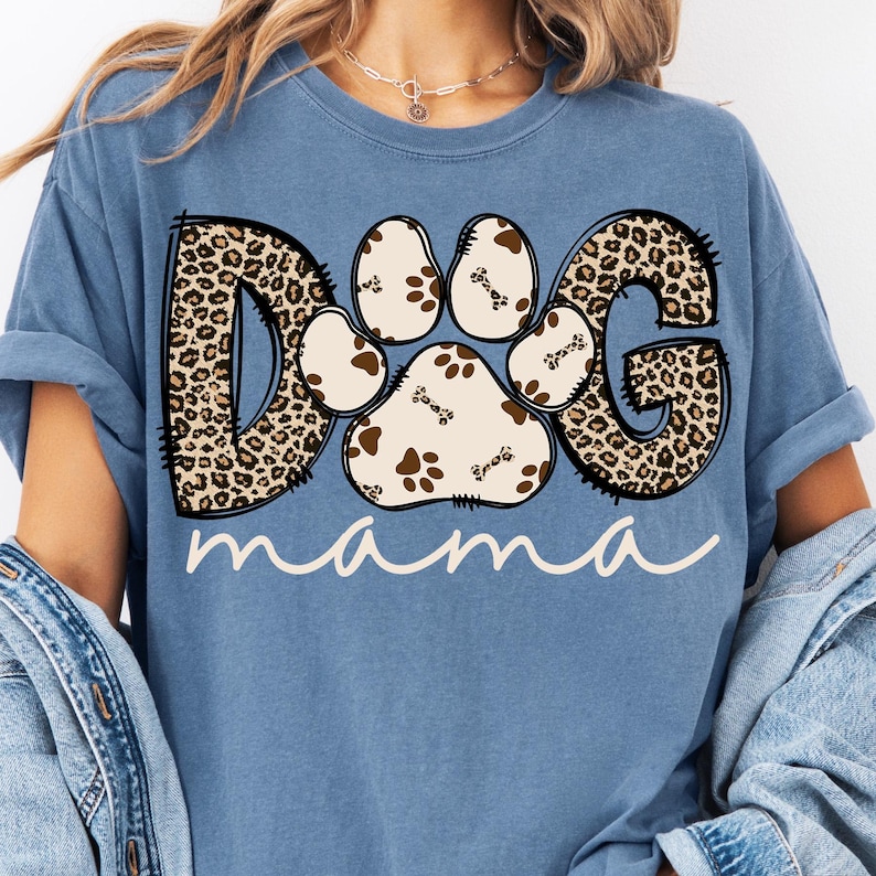 Pu&ograve; includere: Una maglietta blu con un design "DOG" a stampa leopardata con un'impronta di zampa al centro e la parola "mama" sotto.
