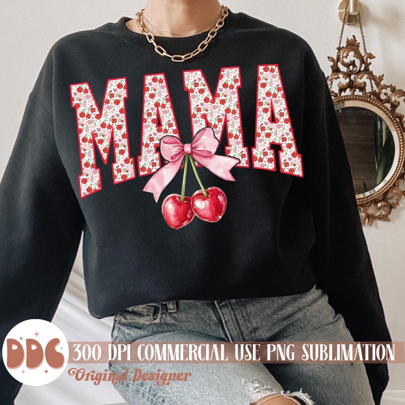 May include: Black sweatshirt with the word "MAMA" in a red and white floral pattern. A pink bow and two red cherries are centered below the word. The sweatshirt is a casual style.