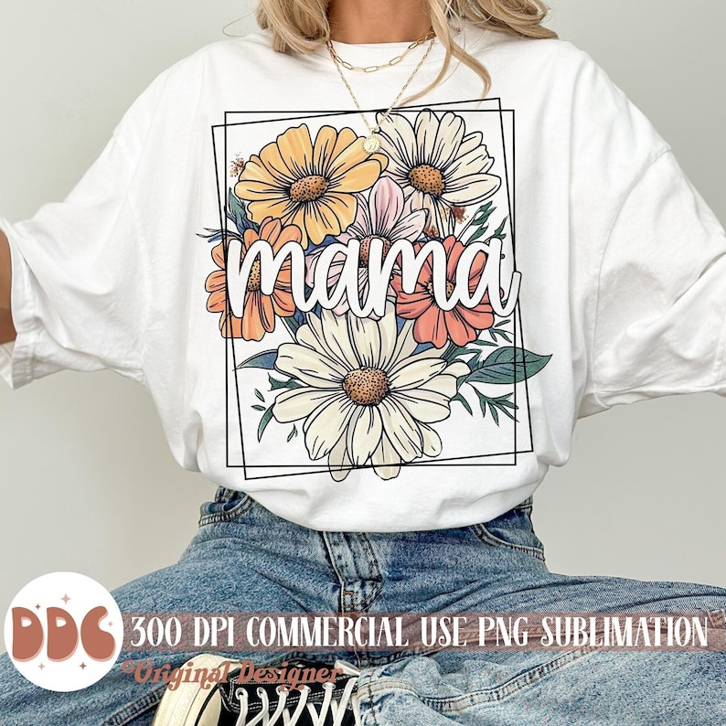 May include: White t-shirt featuring a floral design and the word "mama" in the centre. The flowers are in shades of yellow, orange, pink, and white.