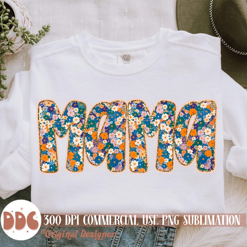 May include: A white sweatshirt with the word "Mama" in orange outlined letters. The letters are filled with a floral pattern of blue, orange, and white flowers.