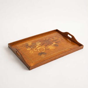 Op de afbeelding: Een rechthoekig houten dienblad met een gepolijste afwerking en geïntegreerde handgrepen aan de korte zijden. Het midden is voorzien van een ingelegd marqueterie-ontwerp met een bloemstuk van rozen en bladeren in diverse bruintinten.