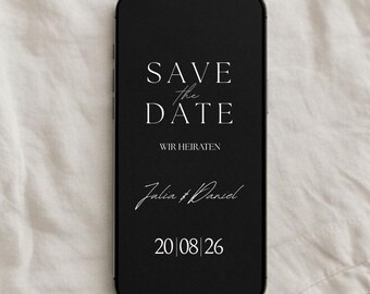 May include: Black smartphone displaying a wedding announcement. The text reads "SAVE the DATE" above "WIR HEIRATEN" and the names "Julia & Daniel" with the date "20 08 26". The phone is set against a white fabric background.