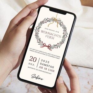 May include: A smartphone displays a Christmas party invitation. The design features a wreath with berries and a bow, with text in German. The invitation includes the date, time, and location for the event.