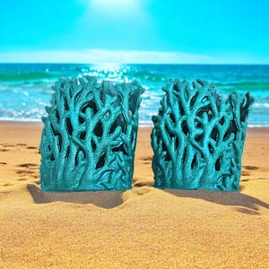 May include: Two teal blue coral-shaped planters on a sandy beach. The planters are made of a textured material that resembles coral.